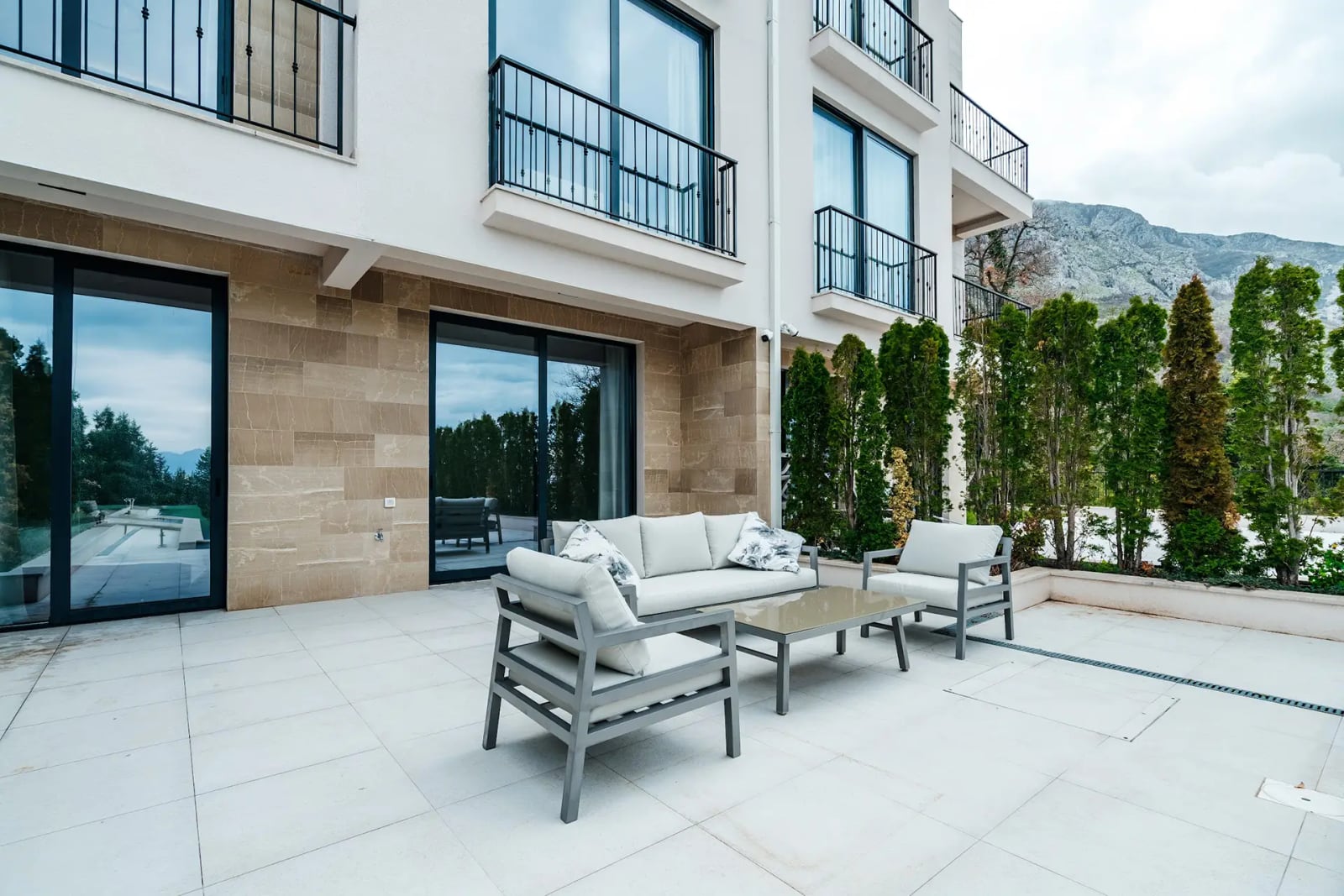 Terrace of a modern villa in Reževići, Montenegro: stone facade finish, lounge area with furniture, and mountain views.
