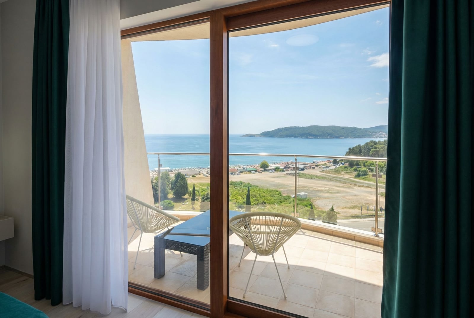 Blick vom Balkon der Wohnung in Bečići, Montenegro: Panoramafenster, geflochtene Möbel und direkter Blick auf die Adria.