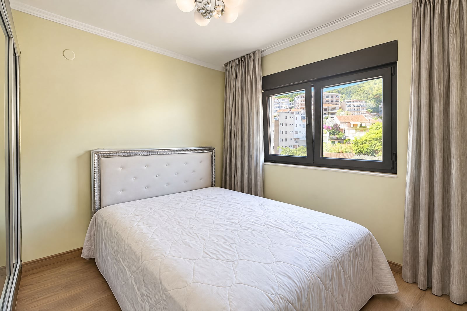 Bright bedroom with a double bed and city view in an apartment in Budva, Montenegro