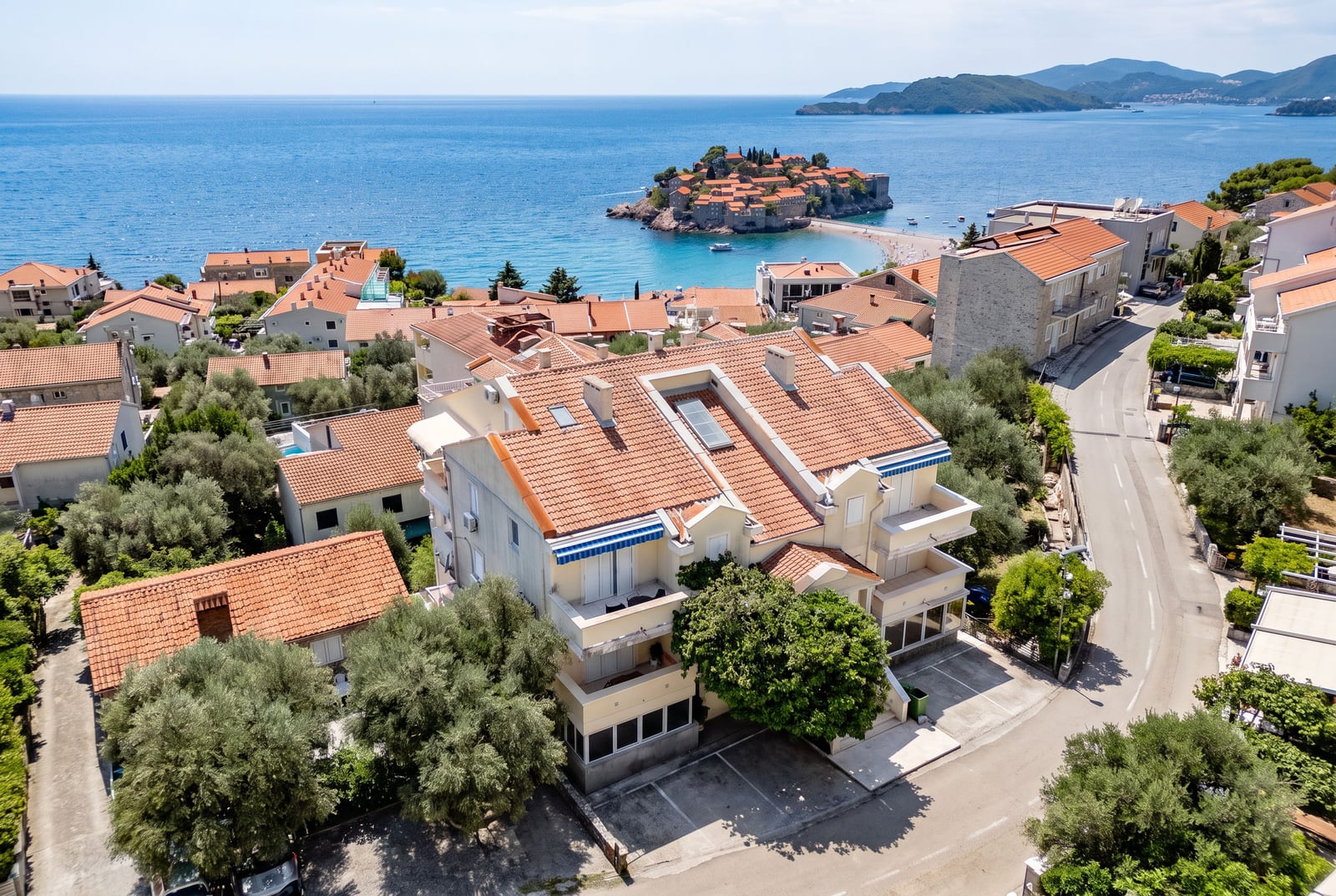 Aerial view of a residential building in Sveti Stefan, Montenegro, with a panoramic view of the island-hotel and the Adriatic Sea.