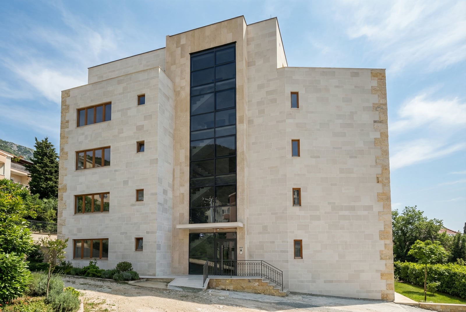 Modern residential building made of light stone with panoramic glazing in Petrovac, Montenegro.