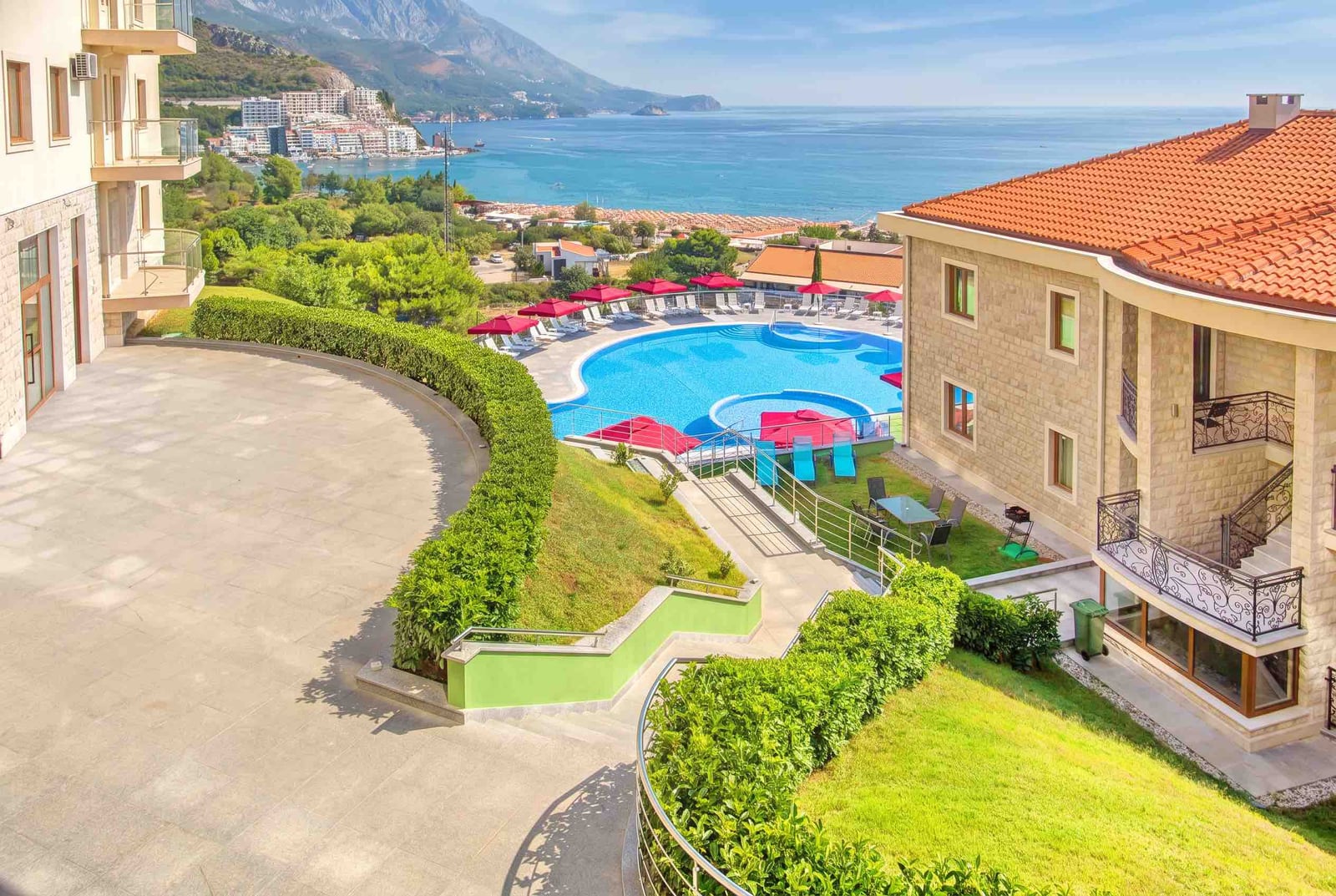 View of the pool and sea from a residential complex in Bečići, Montenegro: terrace, well-maintained grounds, and panoramic landscape.