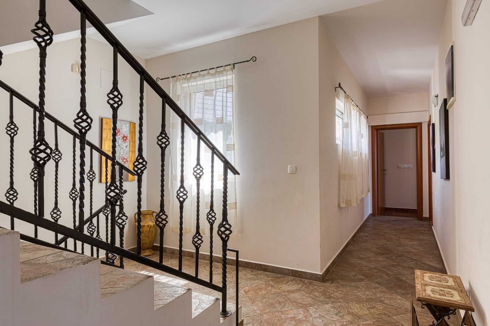 Intérieur d'une villa à Bečići, Monténégro : escalier en fer forgé, hall lumineux avec carrelage et décoration de style classique.