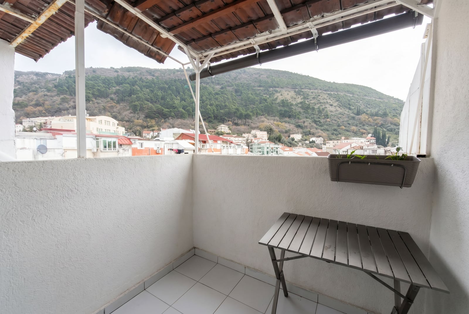 Covered balcony with furniture and views of the mountains and the city in an apartment, Budva, Montenegro.
