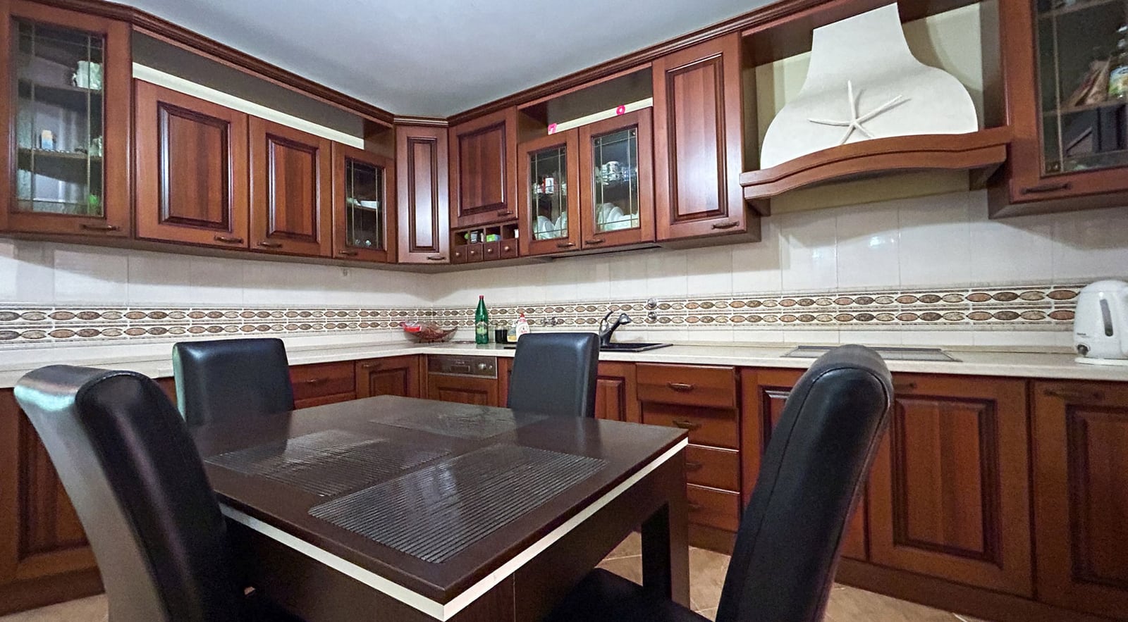 Gemütliche Küche mit Holz-Einbauküche und Essbereich in einer Villa in Dobrota, Montenegro. Innenraum des Hauses Nr. 2609.