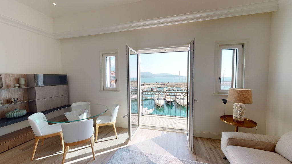 Dnevna soba sa pogledom na marinu i jahte u elitnom stambenom kompleksu Luštica, Crna Gora: moderan nameštaj, svetli enterijer, balkon.