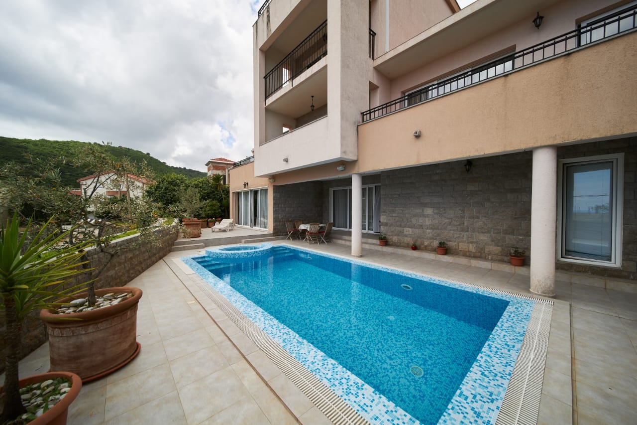 Piscine privée avec espace détente dans une villa à Bečići, Monténégro : finitions modernes en pierre et terrasse aménagée.