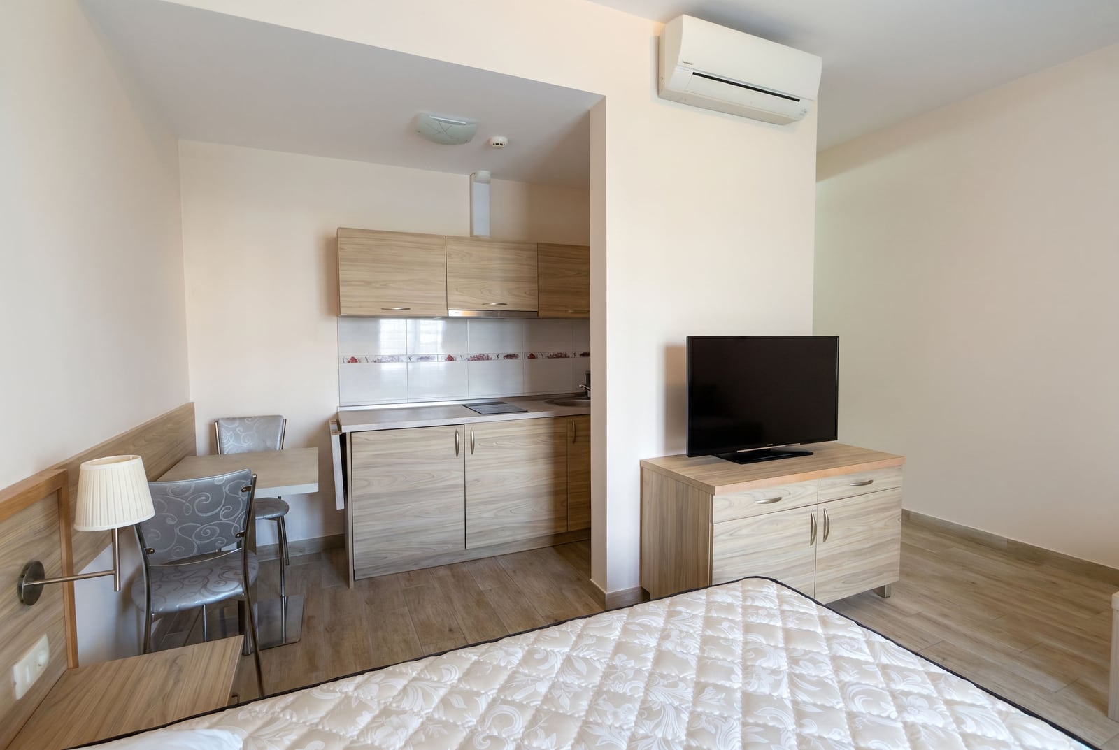 Interior of a living room with an open-plan kitchen in an apartment in Bečići, Montenegro: light-colored furniture, TV area, and dining set.