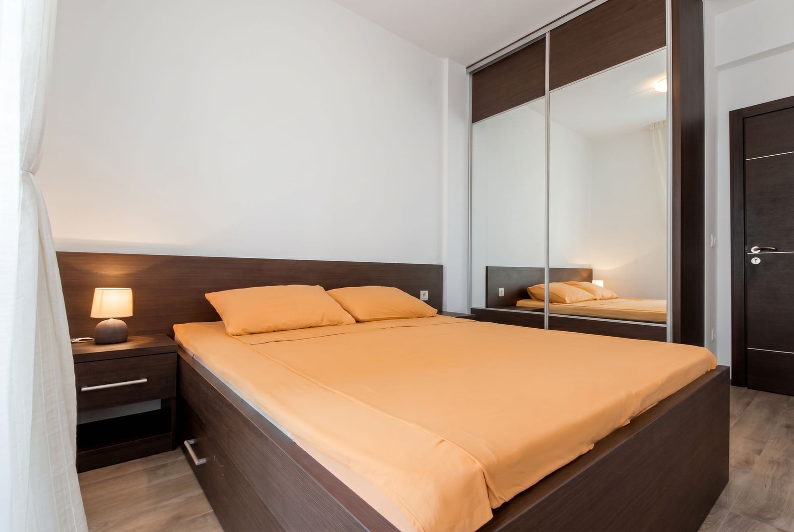 Modern bedroom with a double bed and a mirrored sliding-door wardrobe in an apartment, Budva, Montenegro.