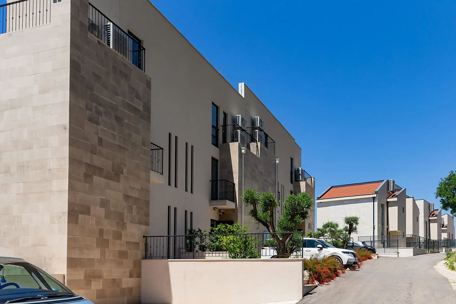 Modern villa in Reževići, Montenegro: stone facade, balconies, parking, and landscaped grounds.