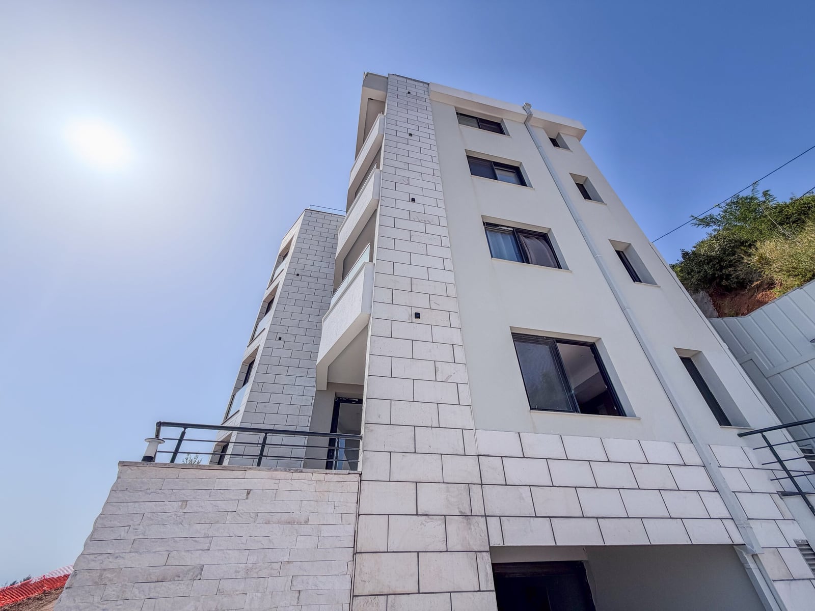 Modern facade of a residential building with stone cladding and balconies in Budva, Montenegro