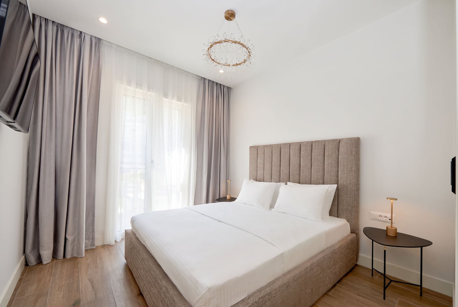Modernes Schlafzimmer mit Doppelbett, Panoramafenster und grauen Vorhängen in einer Wohnung in Luštica, Montenegro