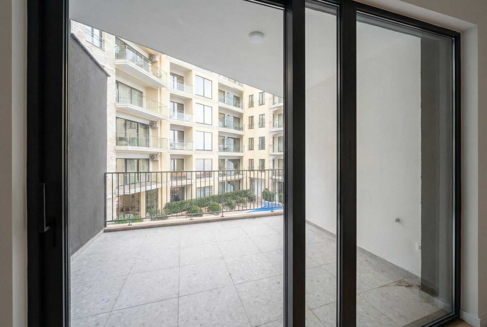 Prostran balkon sa panoramskim pogledom na stambeni kompleks u Bečićima, Crna Gora, sa savremenom završnom obradom i zastakljenjem.