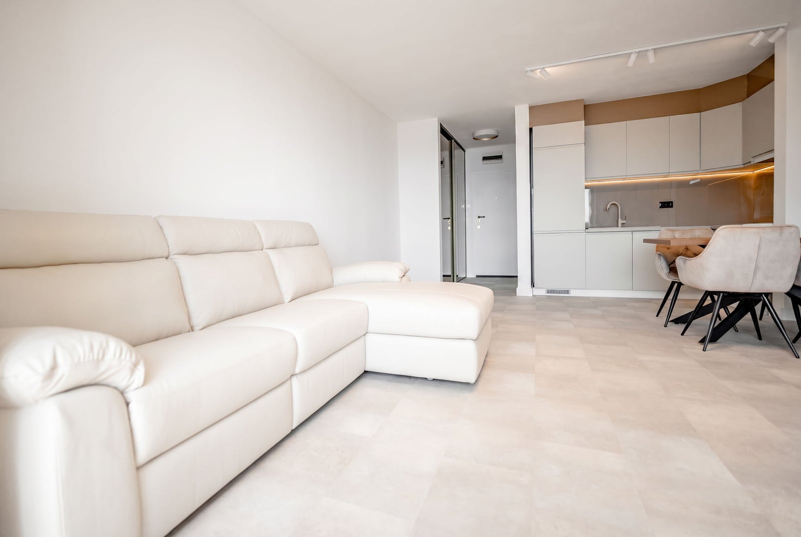 Modern living room with a white leather sofa and kitchen in an apartment in Sveti Stefan, Montenegro. Bright interior.