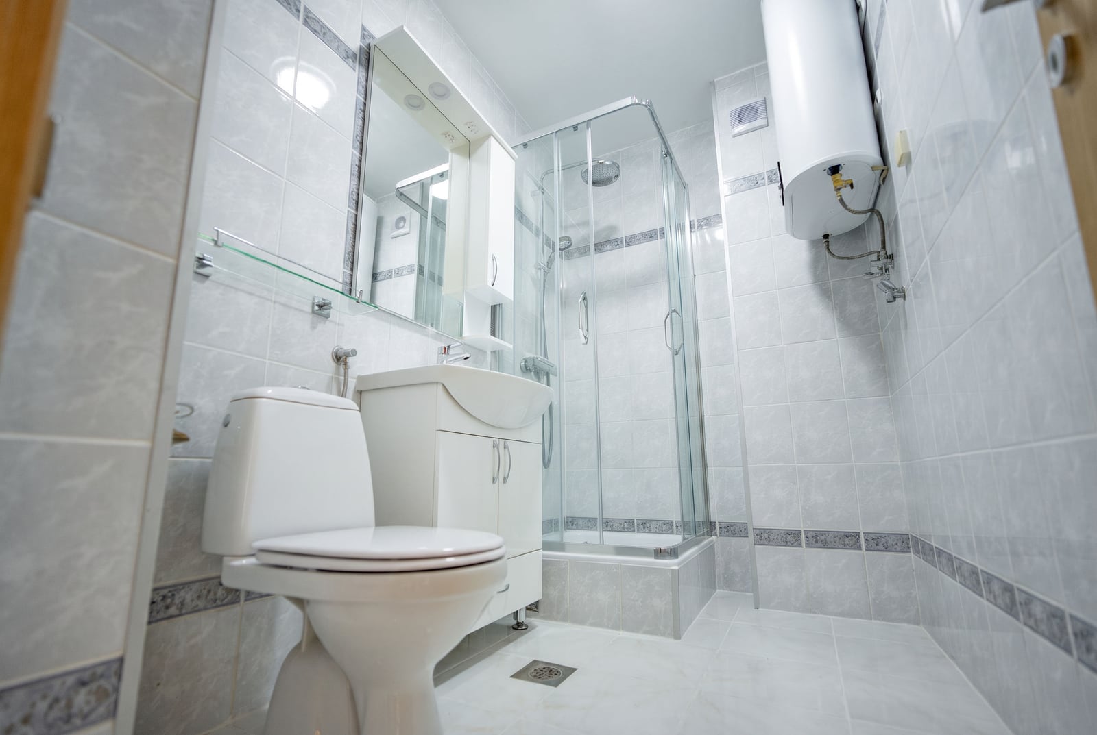 Bright bathroom in an apartment in Sveti Stefan, Montenegro: shower cabin, vanity unit with sink, and water heater.