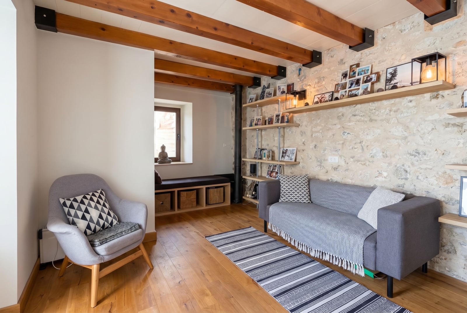 Living room in a house in Budva, Montenegro: stone wall, wooden beams, modern furniture, and a cozy interior.
