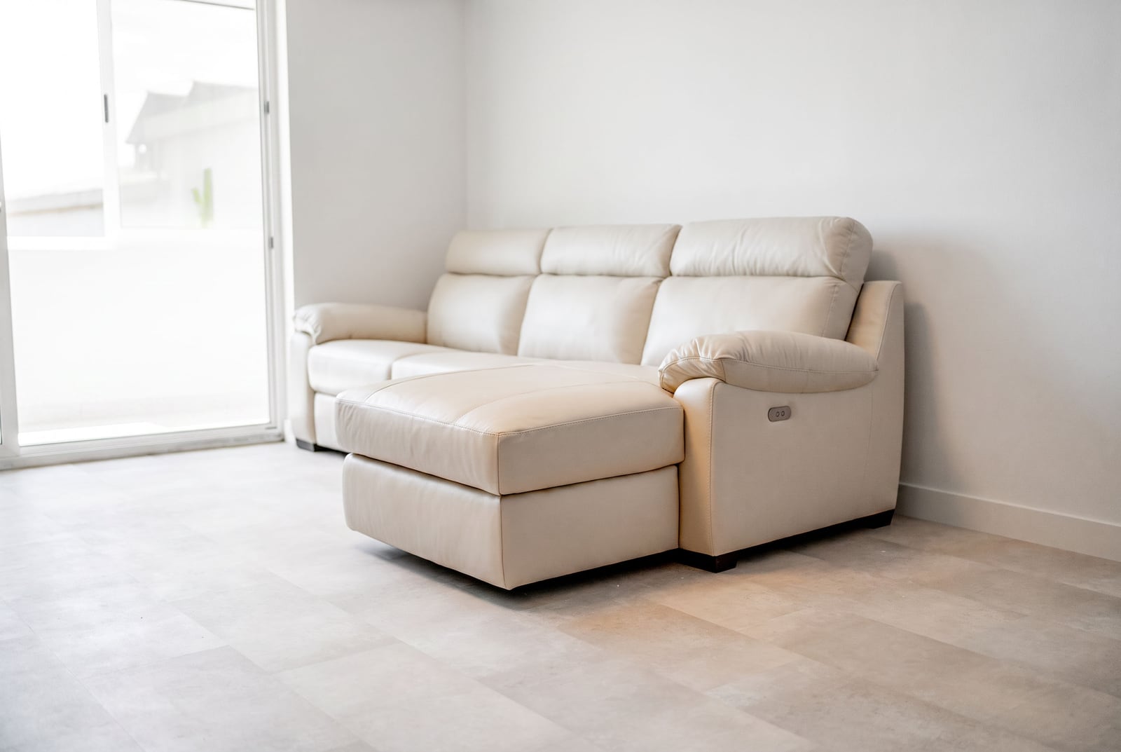 Beige leather sofa in a bright living room of an apartment in Sveti Stefan, Montenegro, with a panoramic window and modern finishes.