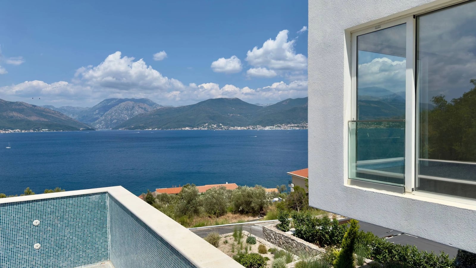 Blick auf das Meer und die Berge vom Pool einer modernen Villa in Krašići, Montenegro: Panoramablick und stilvolle Ausstattung.
