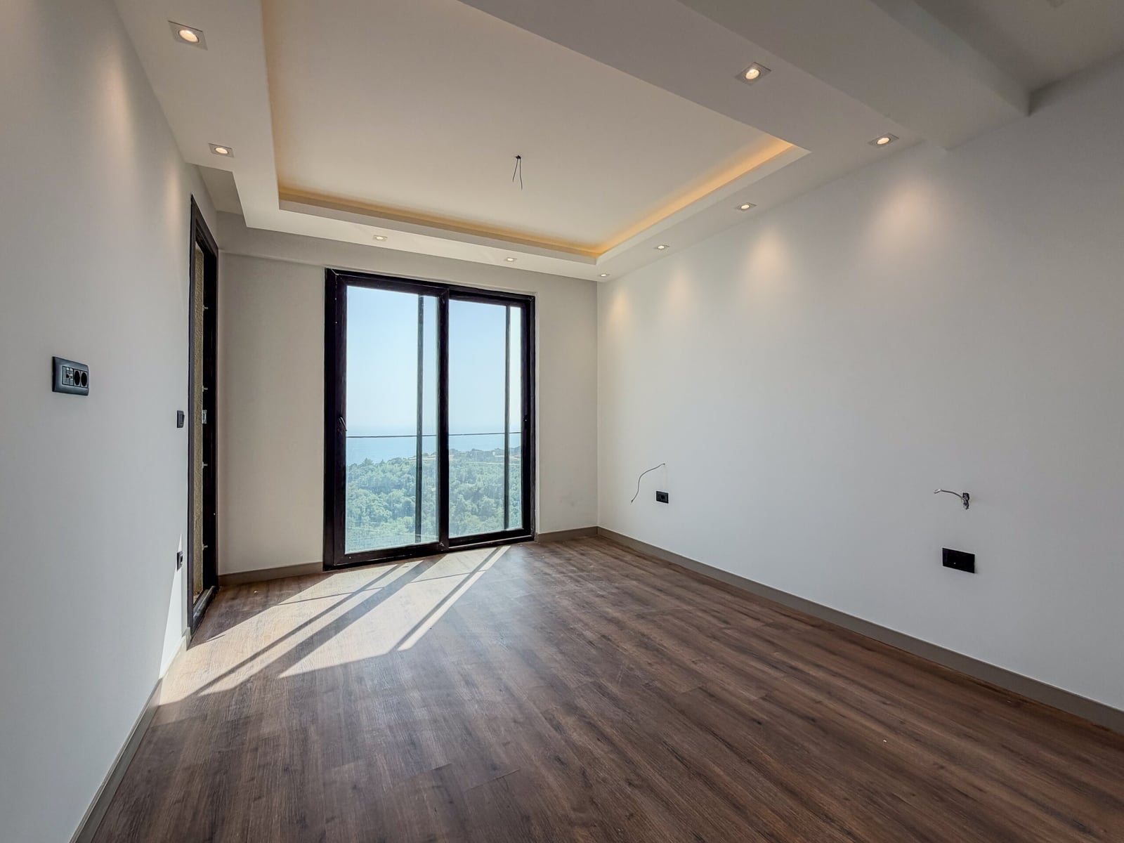 Empty bedroom with parquet flooring, a panoramic window, and a sea view in a new development in Budva, Montenegro