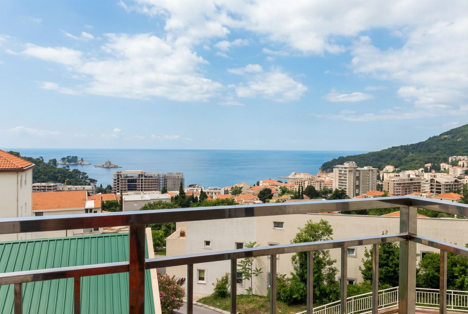 Panoramablick auf das Meer und die Stadt Petrovac, Montenegro, vom Balkon der Wohnung mit modernen Metallgeländern.