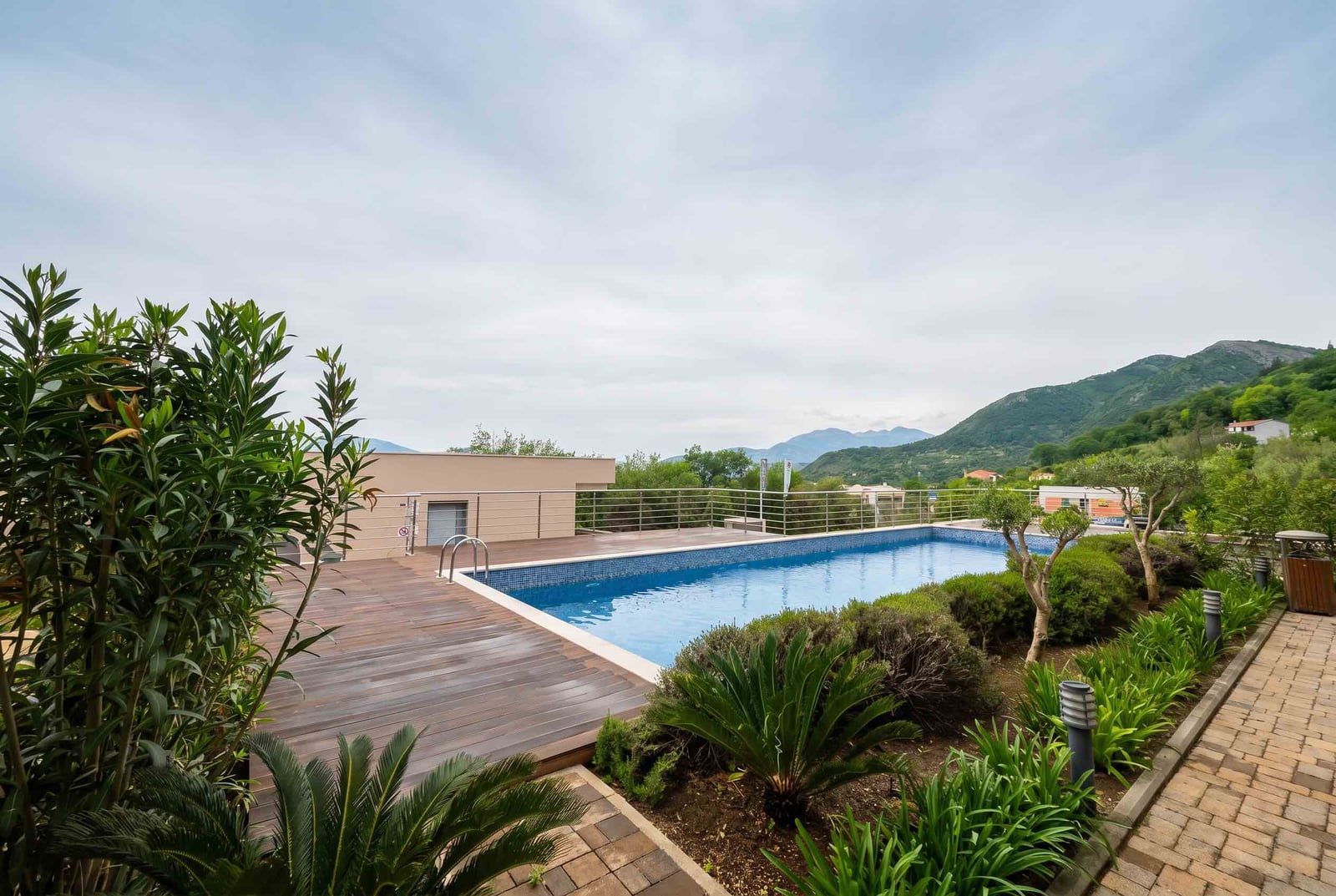 Offener Pool mit Holzterrasse und Bergblick im Wohnkomplex, Kavač, Montenegro.