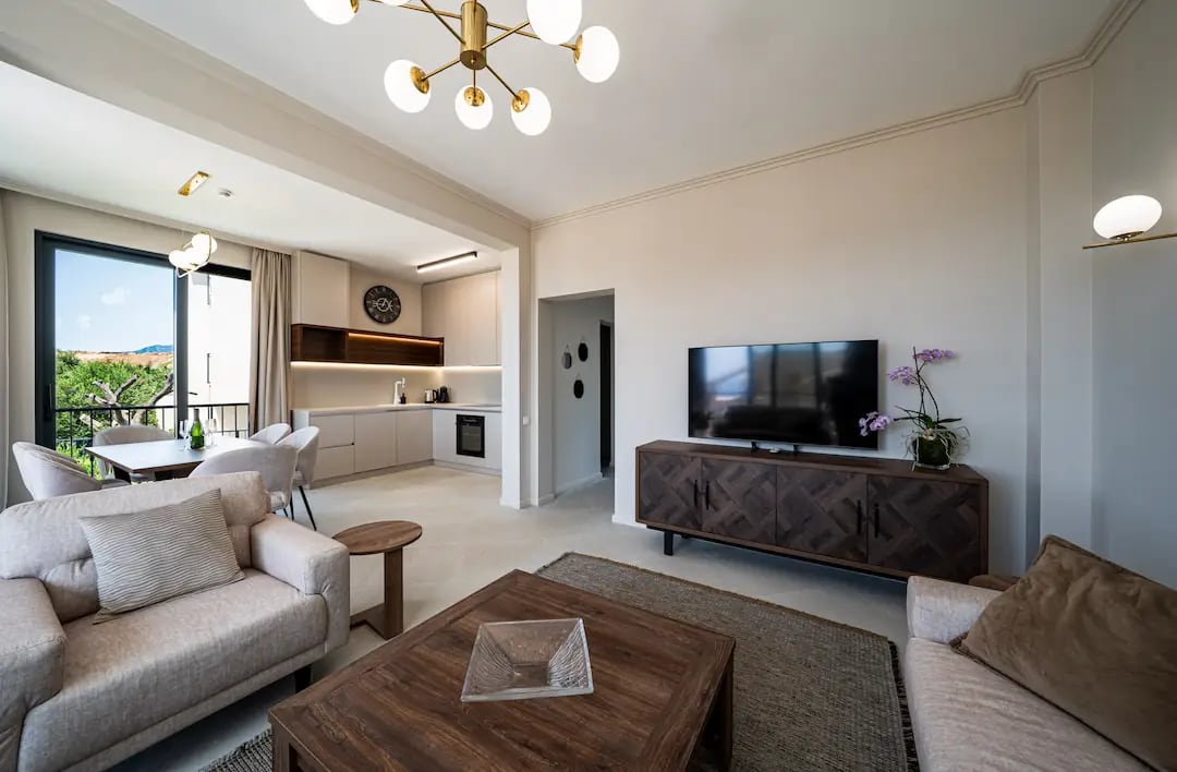 Salon moderne avec cuisine dans une villa à Reževići, Monténégro : intérieur lumineux, mobilier design et vue sur le jardin.