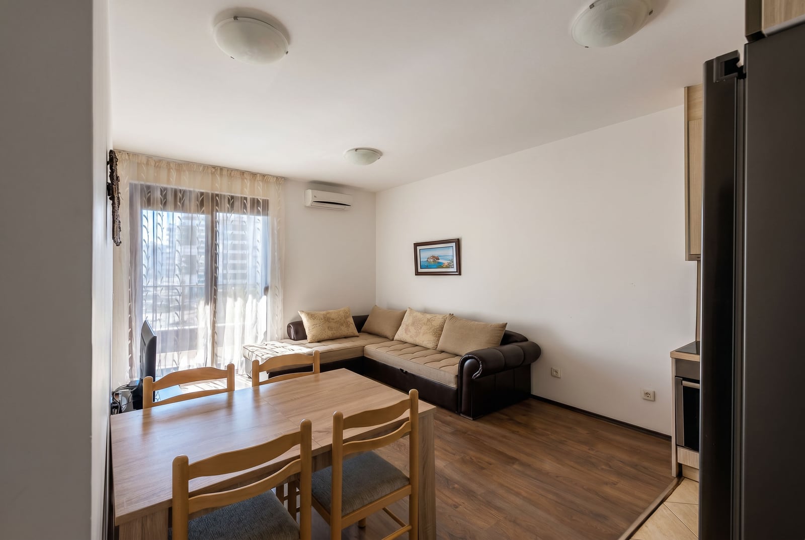 Living room with a corner sofa and dining area in an apartment in Budva, Montenegro: bright interior, access to the balcony.