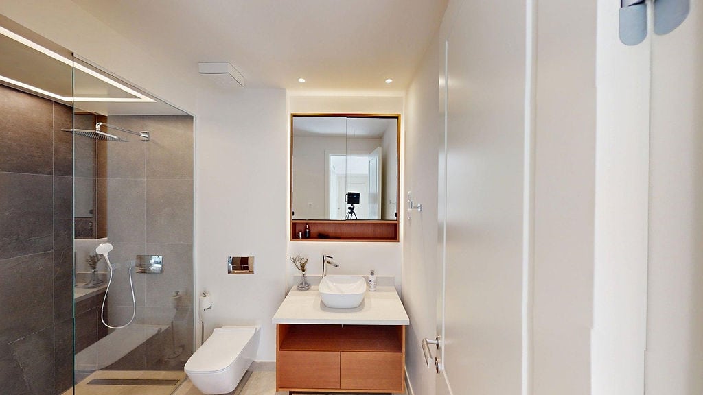 Modernes Badezimmer in einer Wohnung, Luštica, Montenegro: Duschkabine, Waschtisch mit Spiegel und Beleuchtung.