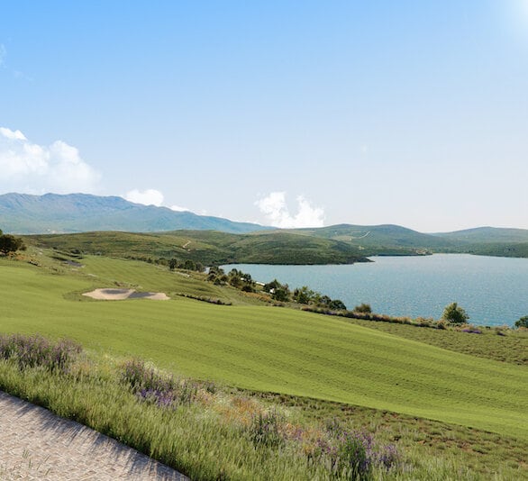 Panoramski pogled na golf teren i more u stambenom kompleksu Luštica Bay, Crna Gora: zelene livade i planinski pejzaž.