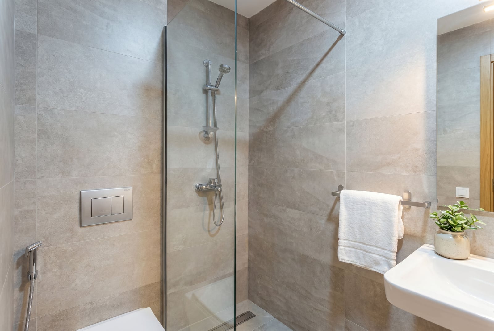 Modern bathroom in an apartment in Bečići, Montenegro: walk-in shower, grey tiles, and premium-quality sanitary ware.