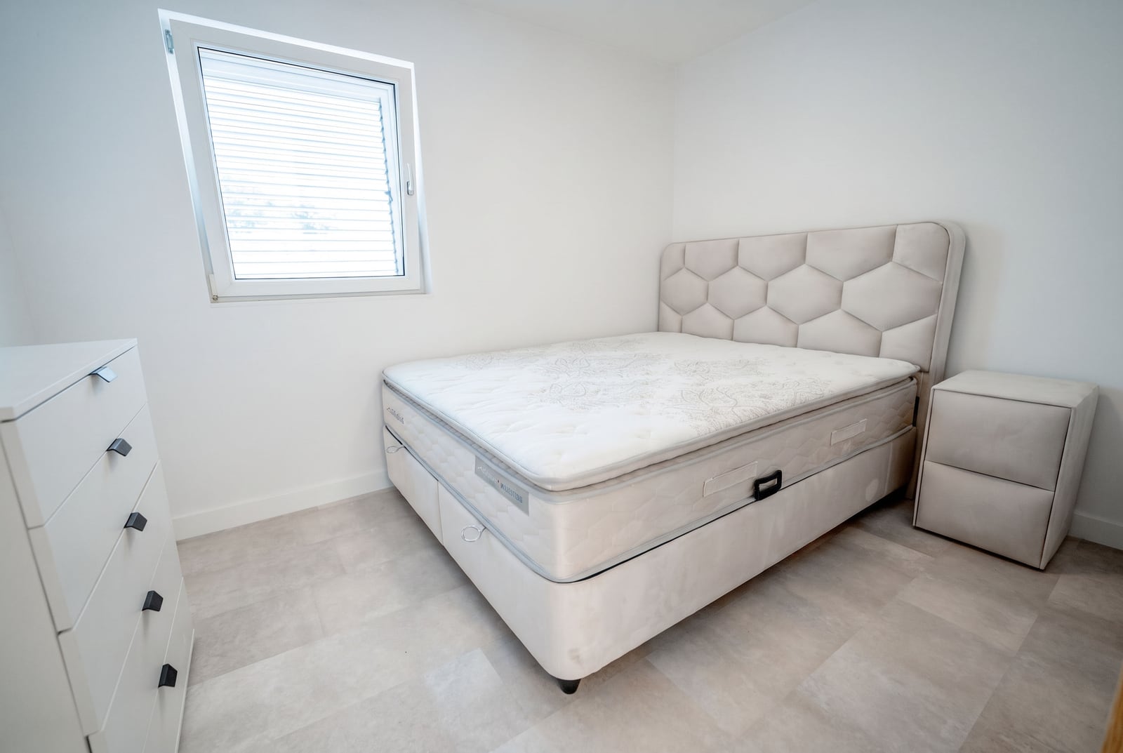 Bright bedroom with a double bed and dresser in an apartment at the Sveti Stefan resort, Montenegro.