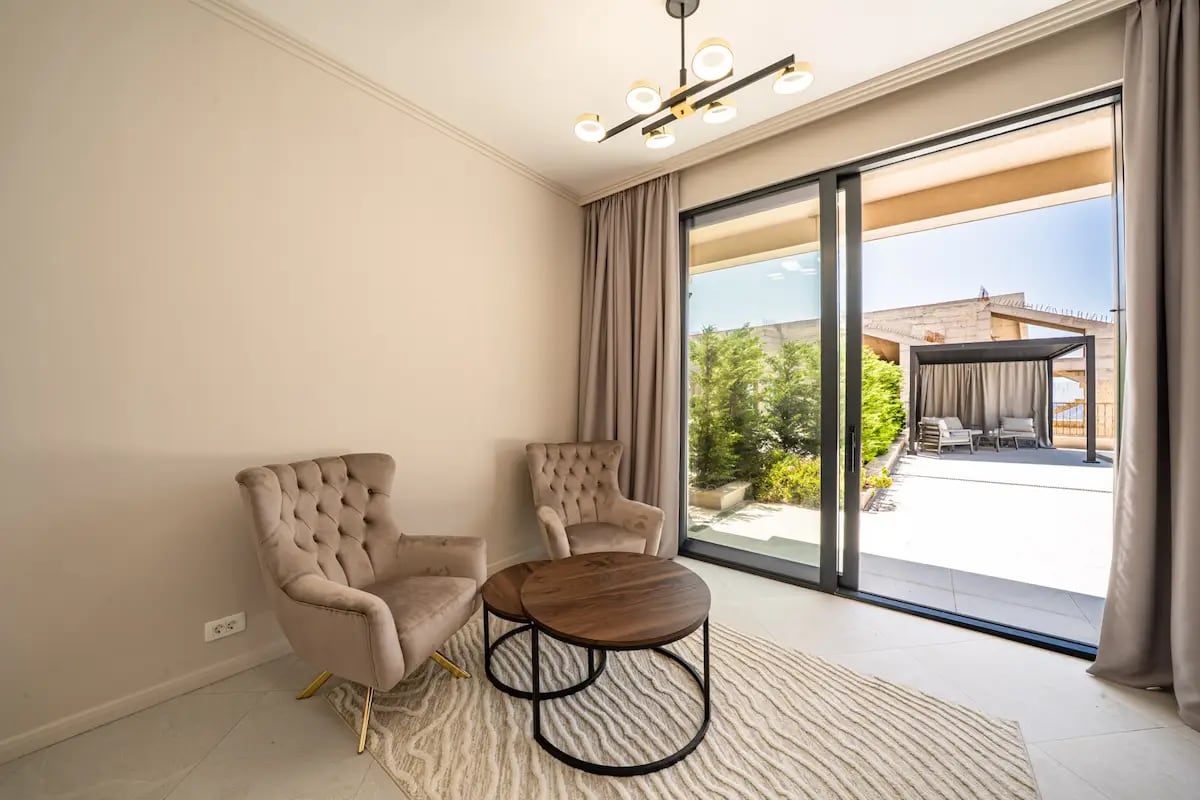 Salon avec fauteuils confortables et accès panoramique à la terrasse de la villa à Reževići, Monténégro.