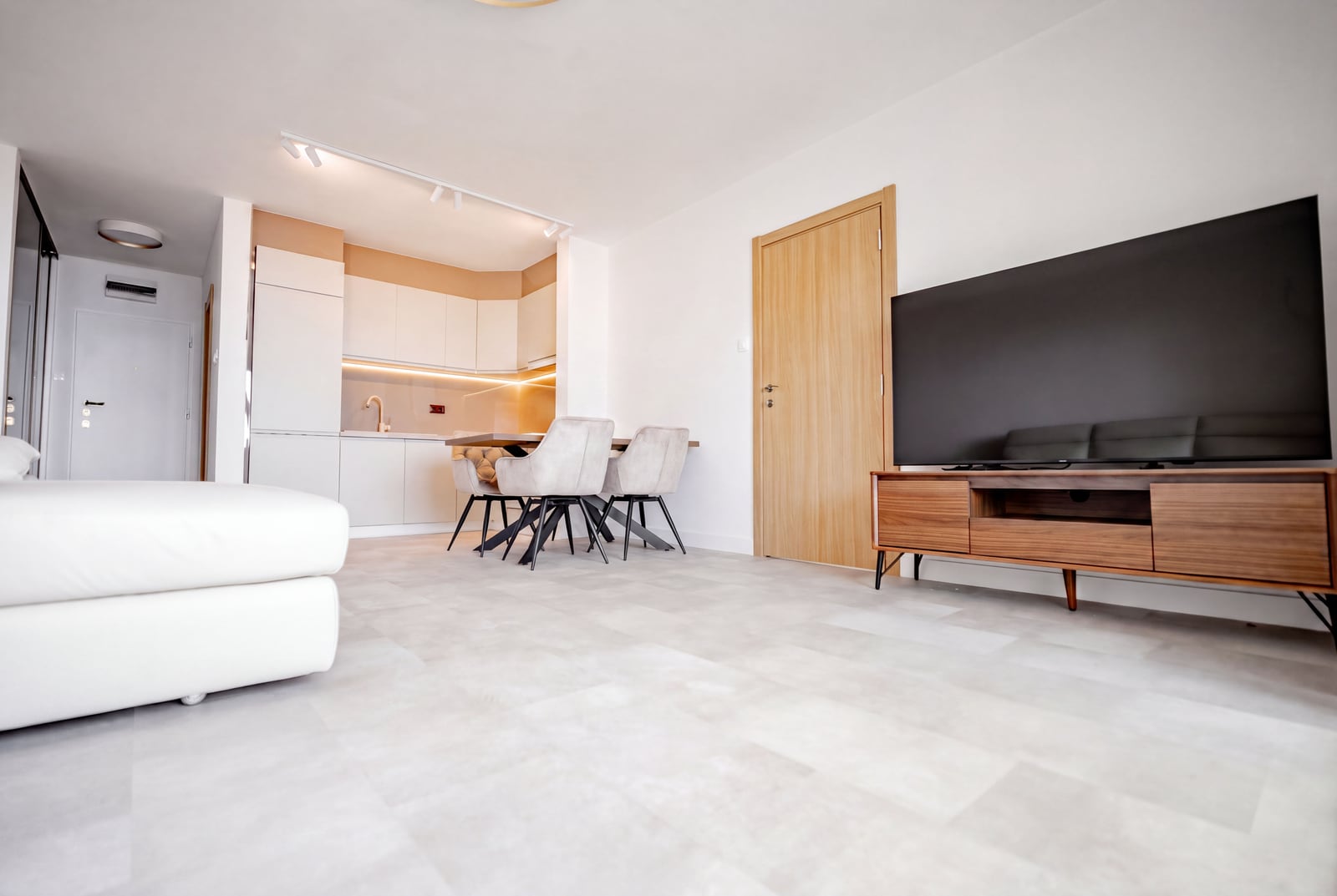 Modern living room with kitchen in an apartment in Sveti Stefan, Montenegro: bright interior, TV area, and dining set.