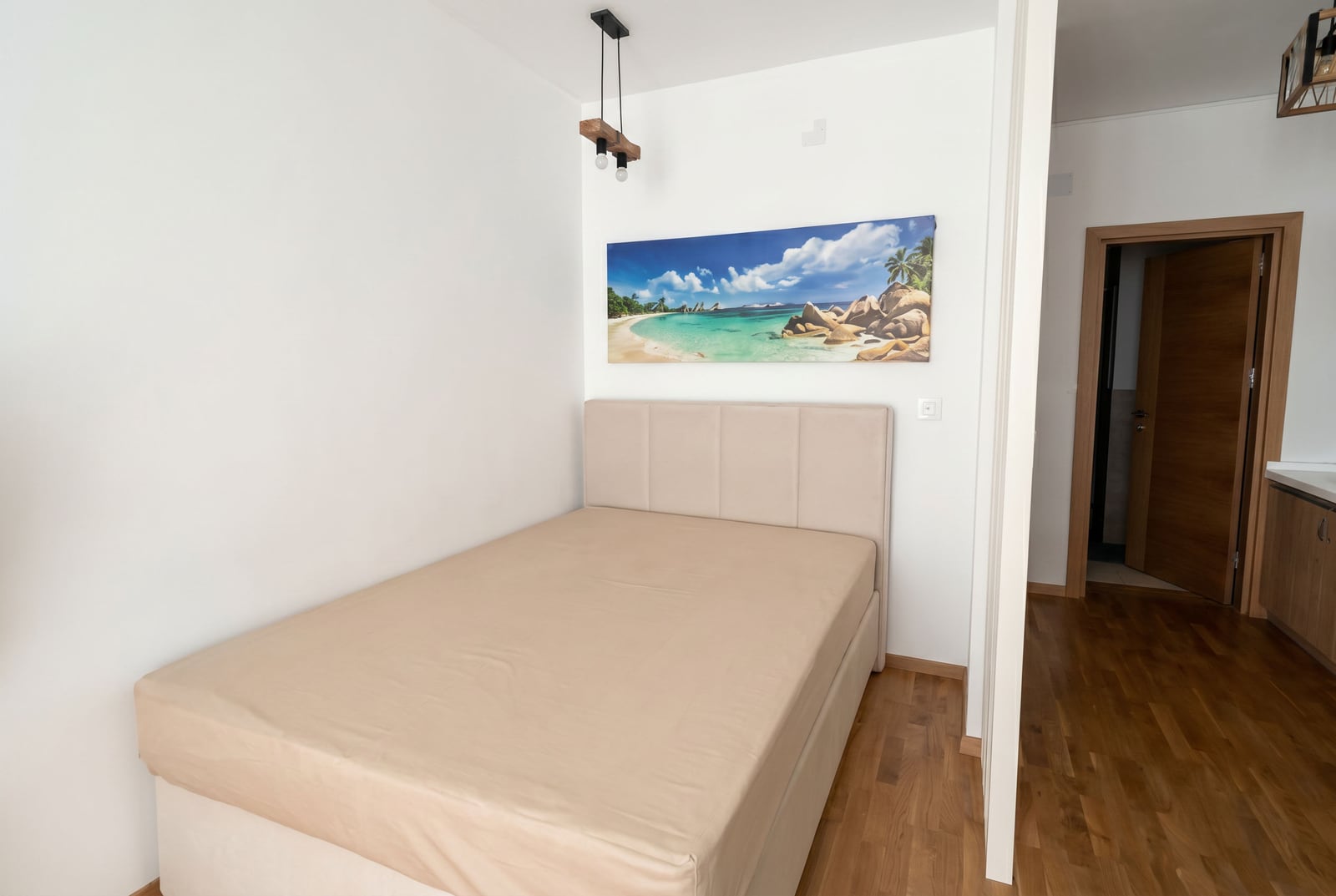 Gemütliches Schlafzimmer mit Doppelbett in einem Apartment in Bečići, Montenegro: modernes Interieur, Parkettboden und Wanddekoration.
