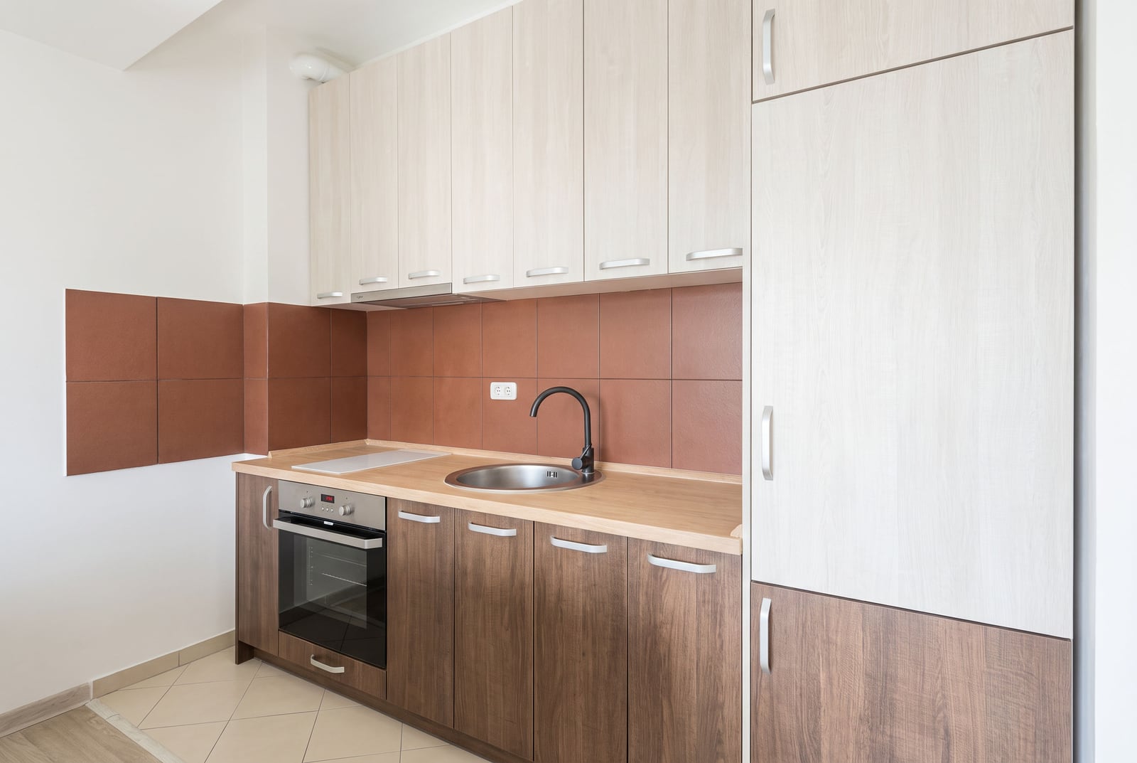 Modern kitchen in an apartment in Budva, Montenegro: light furniture, brown tile, and built-in appliances