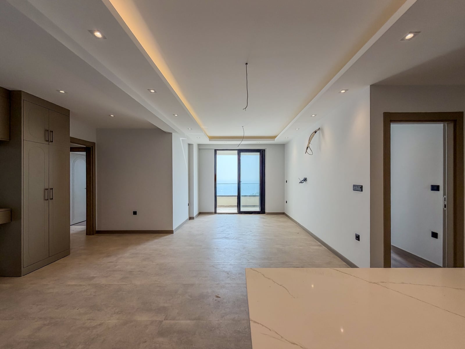 Spacious living room with finished interior, built-in wardrobe, and access to a balcony with sea view in Budva, Montenegro