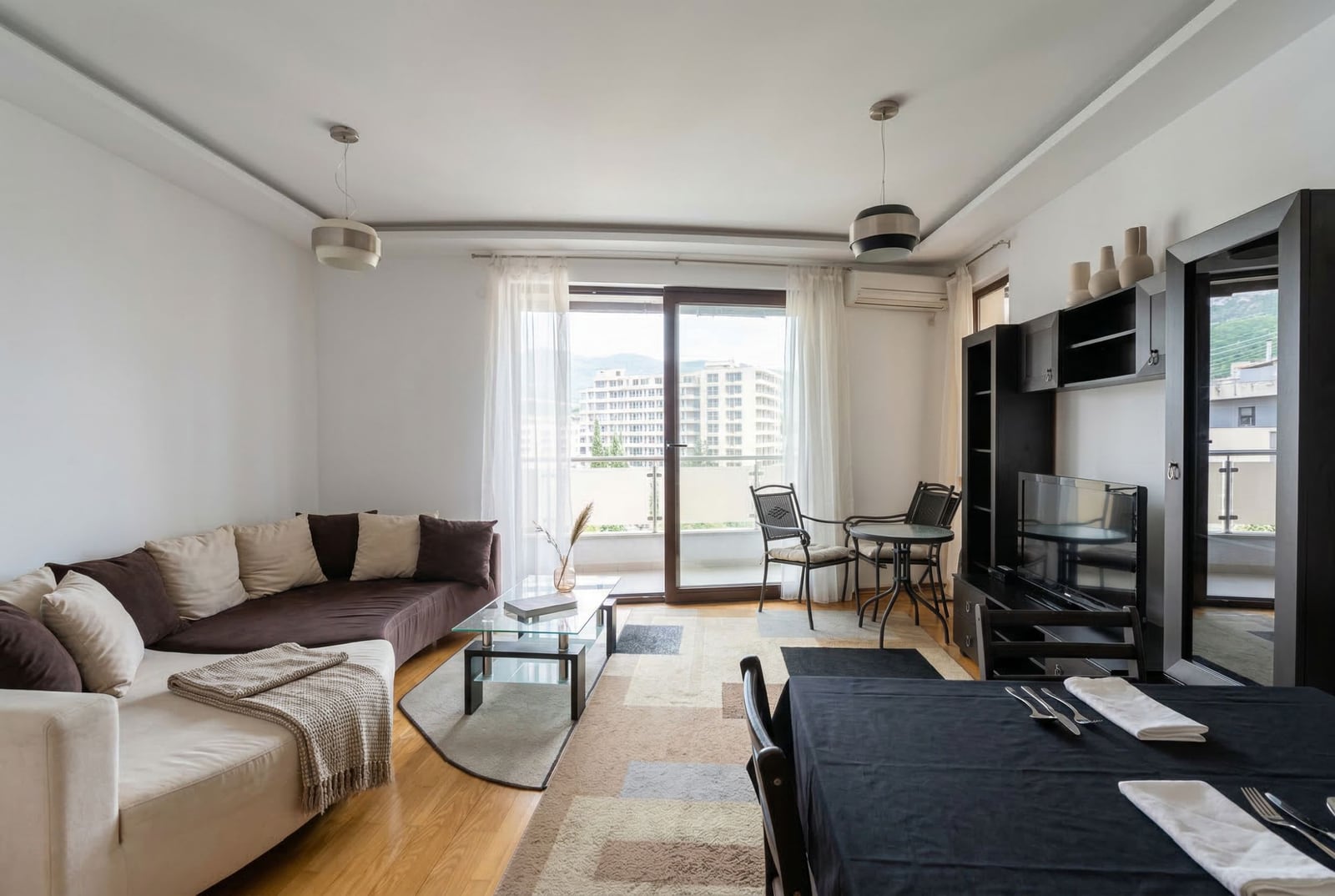 Dnevna soba u stanu u Budvi, Crna Gora: ugaona garnitura, trpezarijski deo, izlaz na balkon sa panoramskim pogledom.