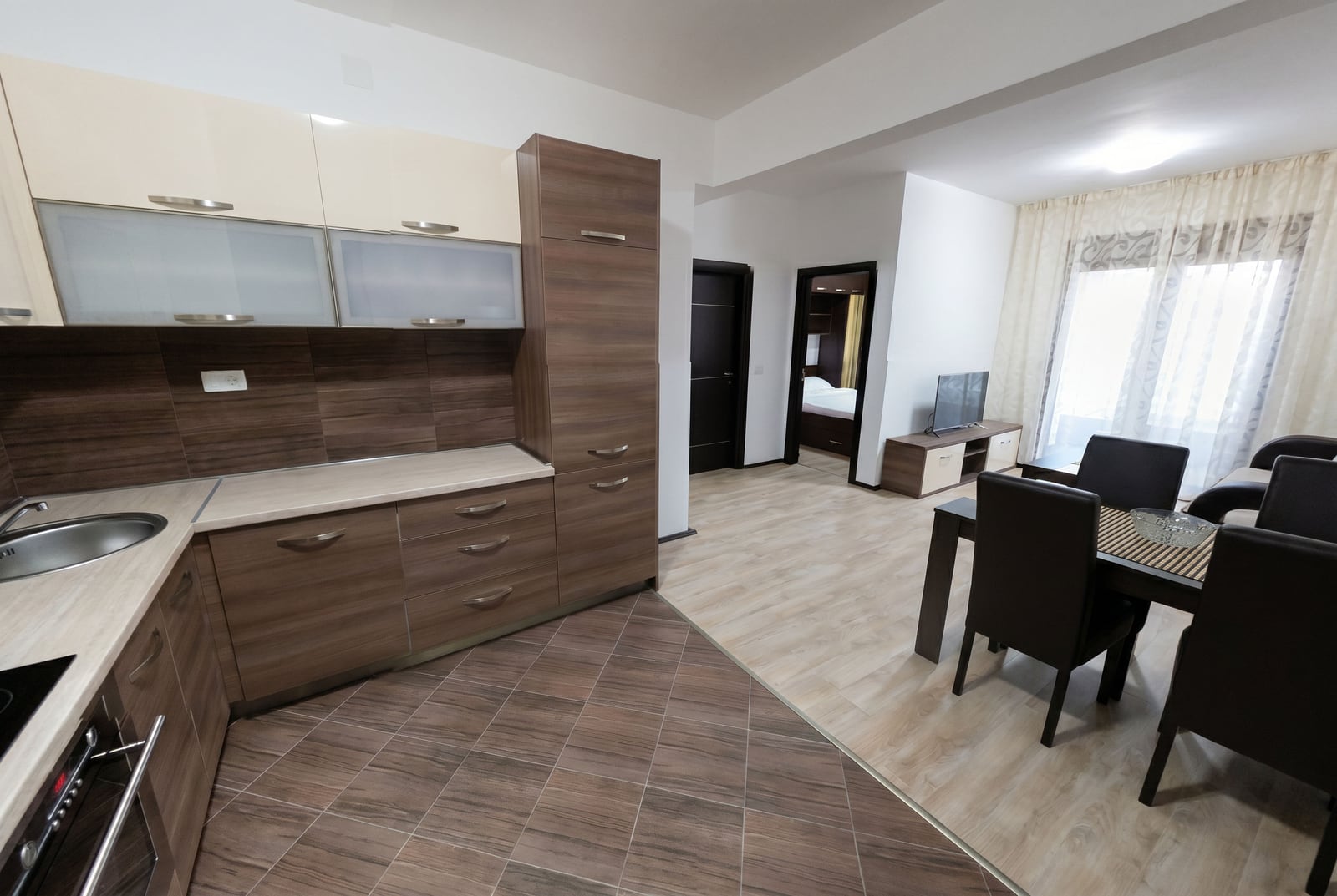 Modern open-plan kitchen and living room with furniture in a Budva apartment, Montenegro: dining area and view of the bedroom.