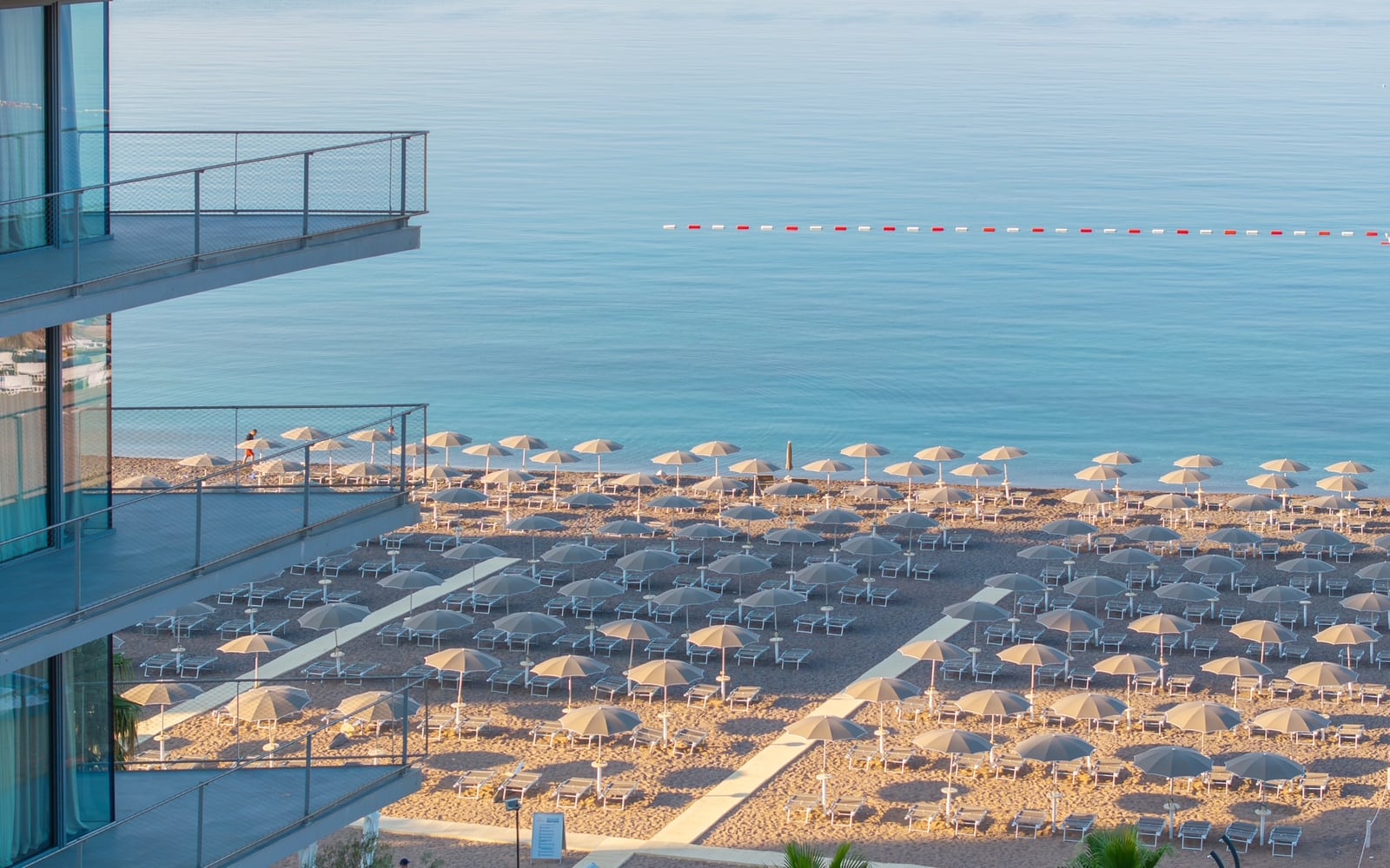Panoramski pogled na peščanu plažu sa ležaljkama i Jadransko more sa balkona apartmana u Bečićima, Crna Gora