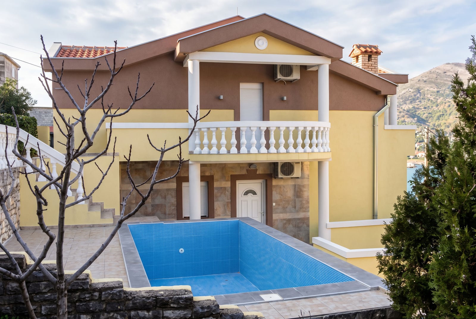 Two-story house in Tivat, Montenegro, with an outdoor pool, balcony, and mountain view.