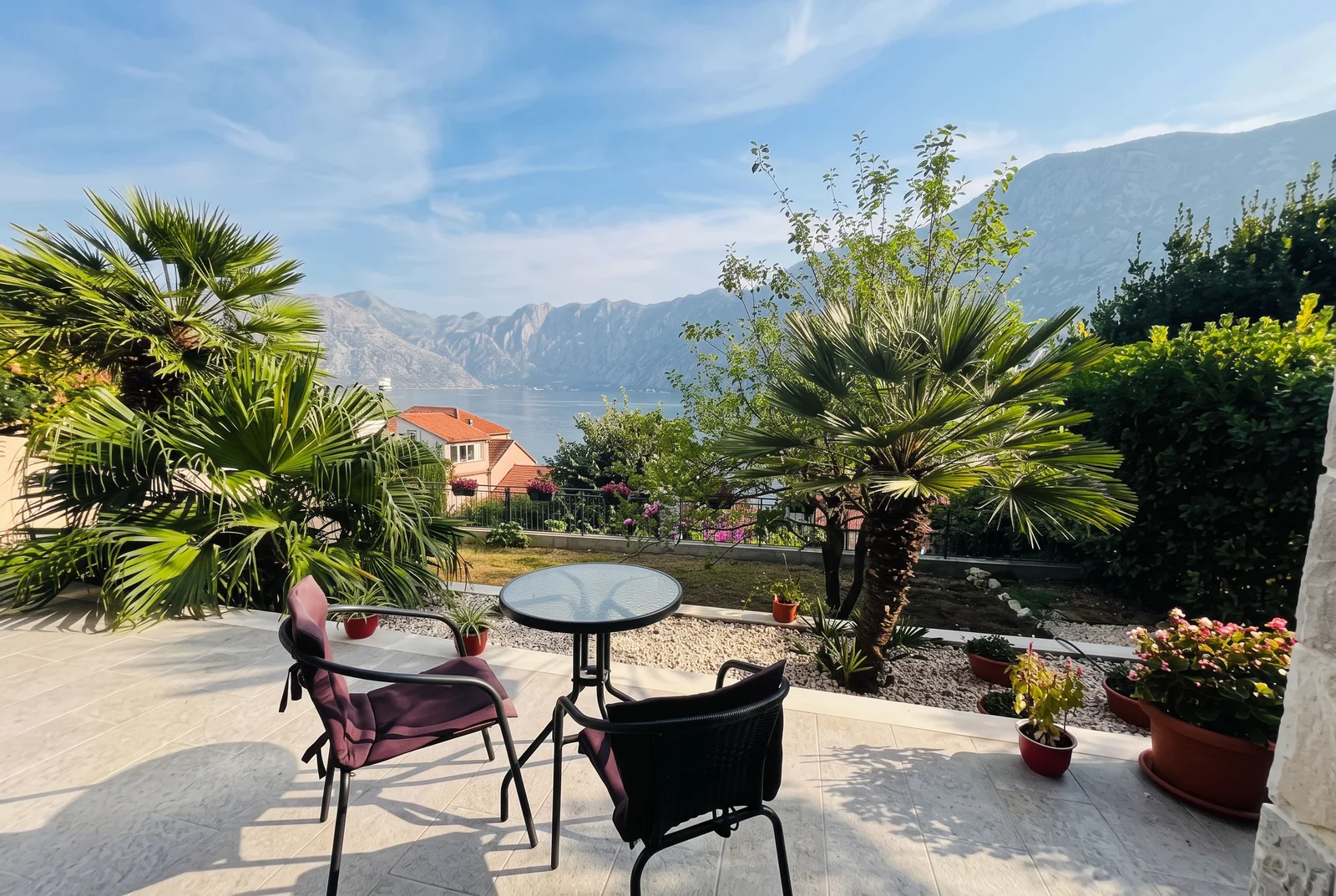 Terasa sa pogledom na more i planine, baštenski mobilijar, palmе i cvetne leje.