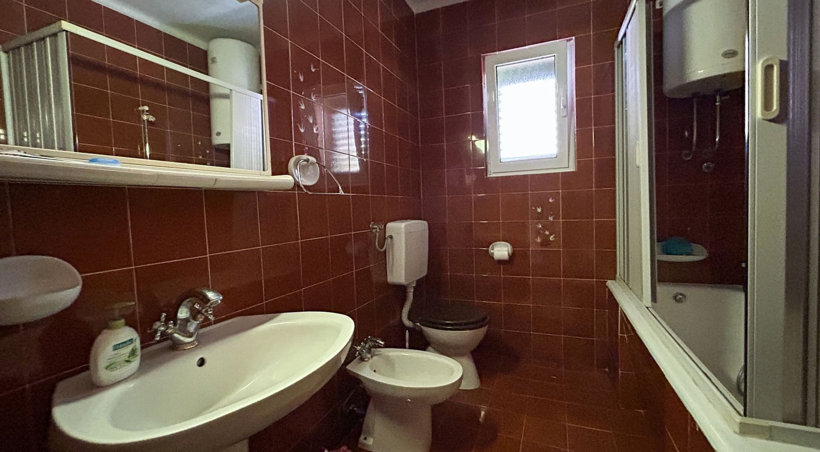 Badezimmer mit braunen Fliesen, Duschkabine und Bidet in einer Villa in Dobrota, Montenegro.