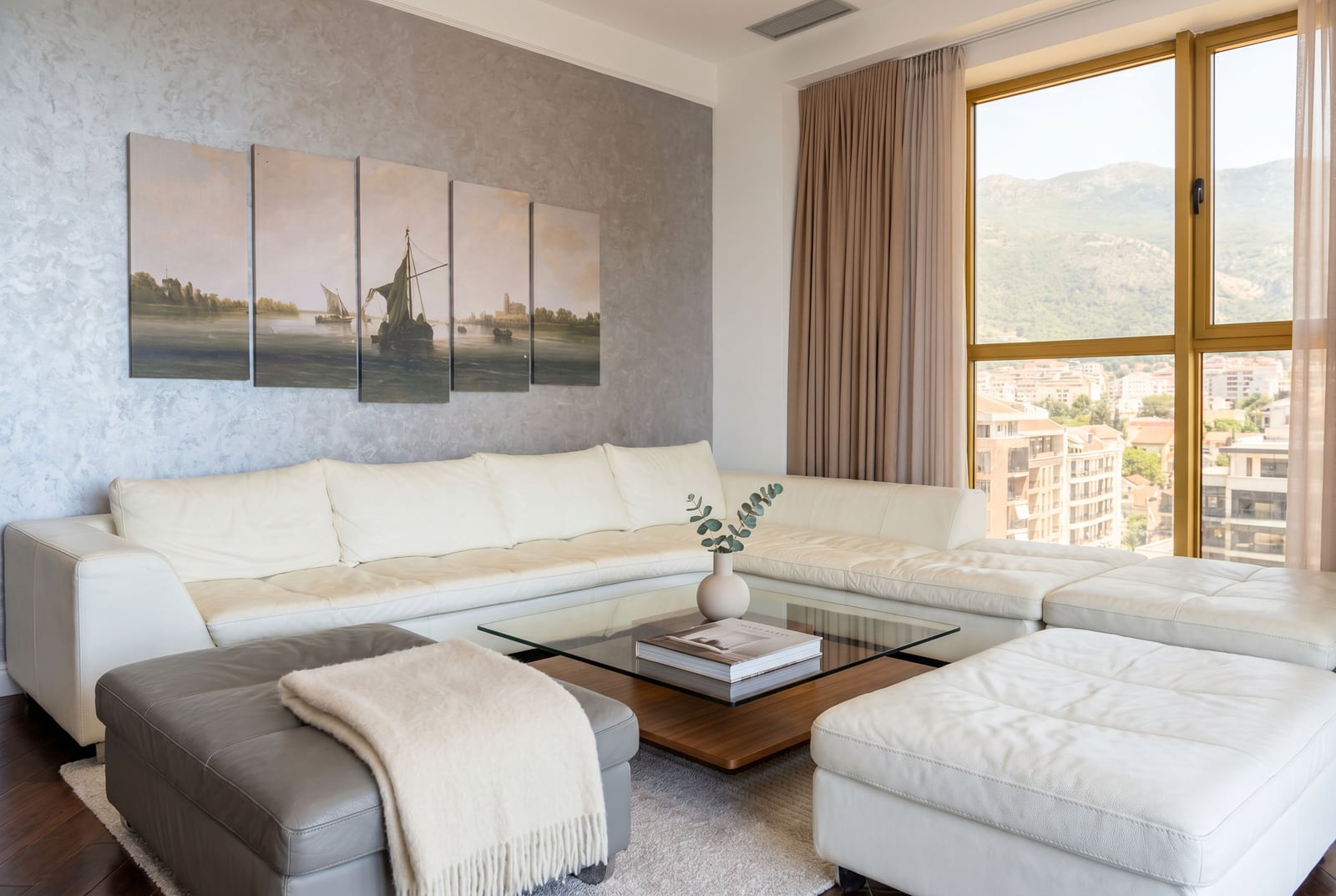 Modern living room with a white leather sofa and mountain views in an apartment in Budva, Montenegro.