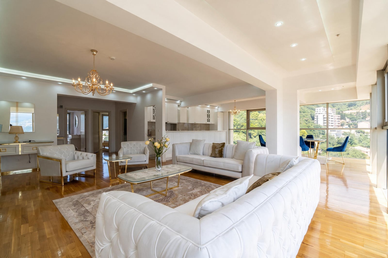 Spacious living room with white sofas and panoramic windows in an apartment in Bečići, Montenegro.