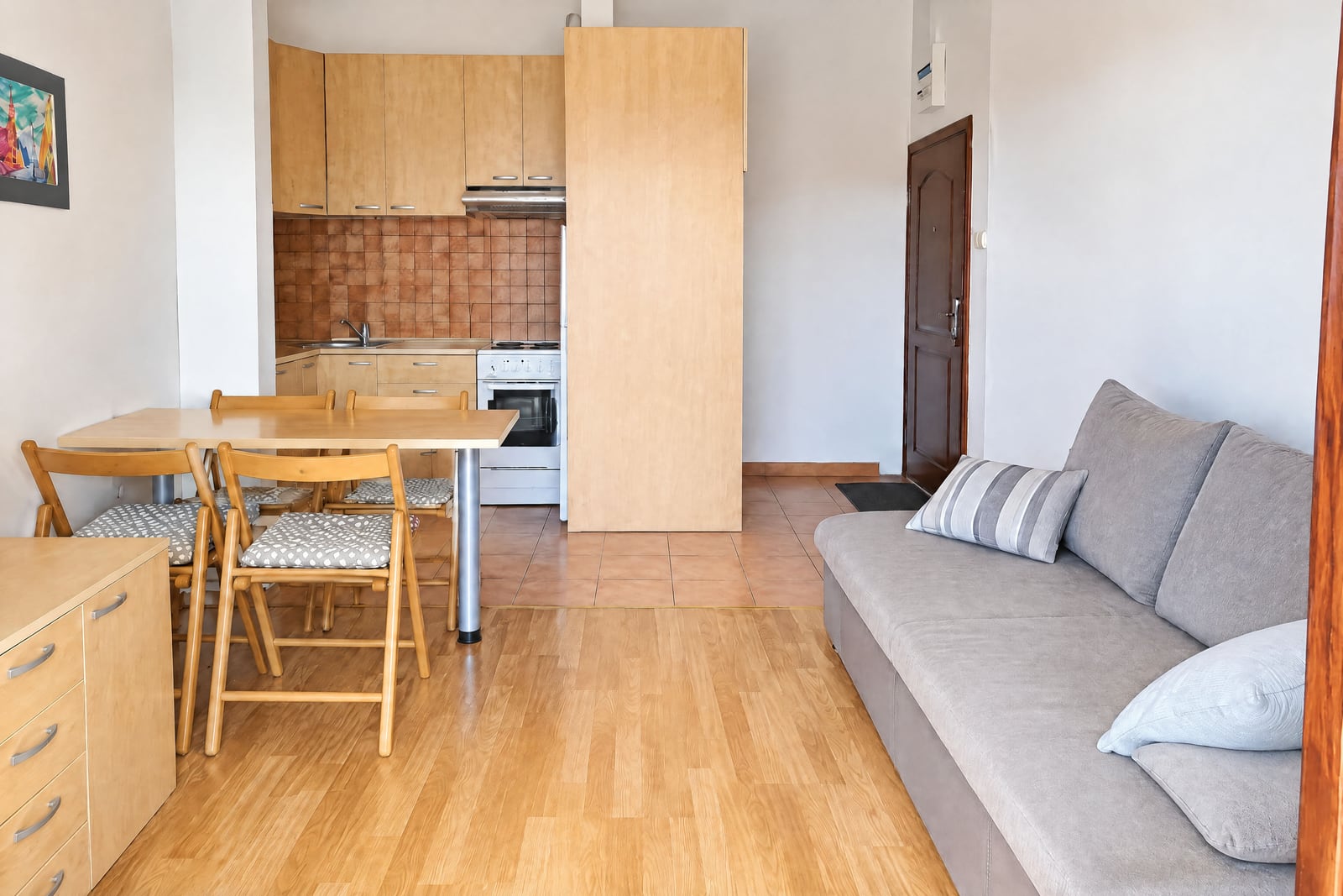Living room with a gray sofa, dining area, and kitchen in an apartment in Becici, Montenegro