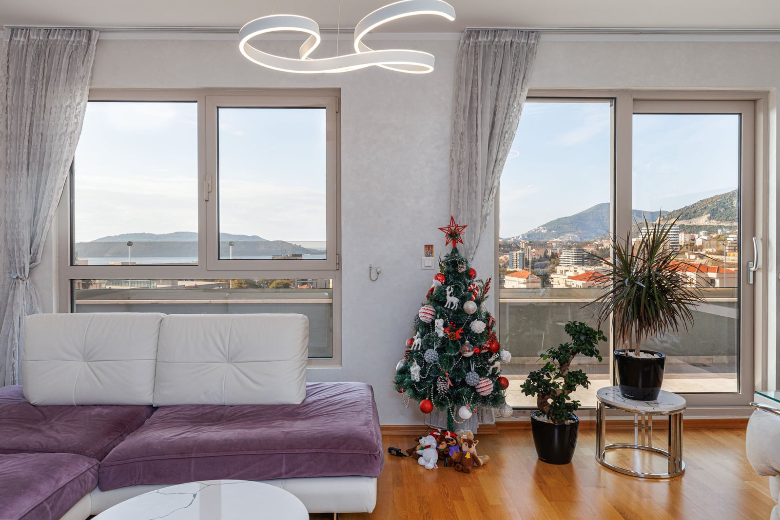 Living room in a penthouse in Bečići, Montenegro: panoramic windows with a sea view, modern furniture and decor.