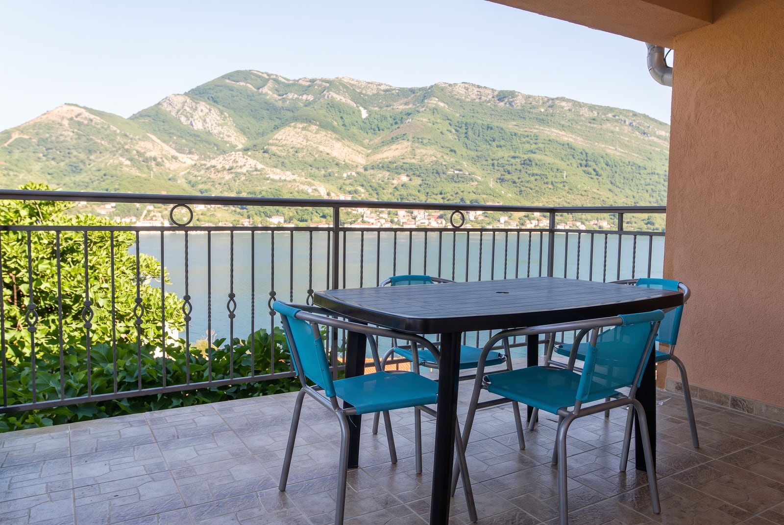 Balcony with furniture and panoramic views of the sea and mountains in a house in Tivat, Montenegro.