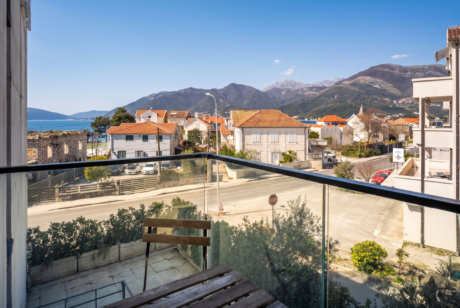 Pogled sa balkona stana u Tivtu, Crna Gora: panorama na planine, more i gradsku izgradnju.