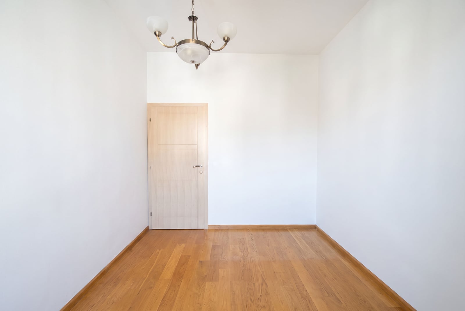 Empty bedroom with white walls, parquet flooring, and an interior door in an apartment in Bečići, Montenegro.