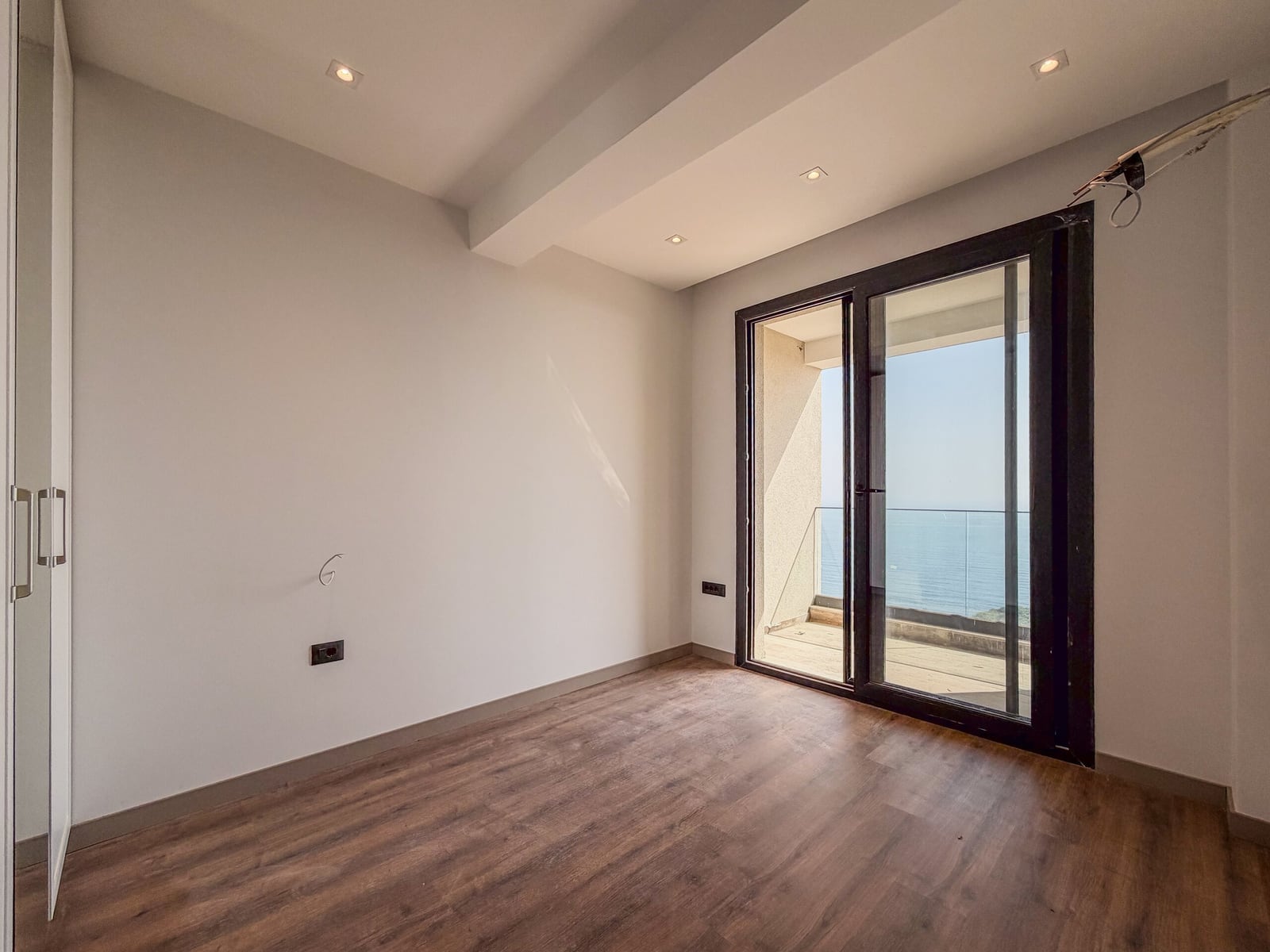 Bright bedroom with a panoramic window, sea view, and parquet flooring in an apartment in Budva, Montenegro